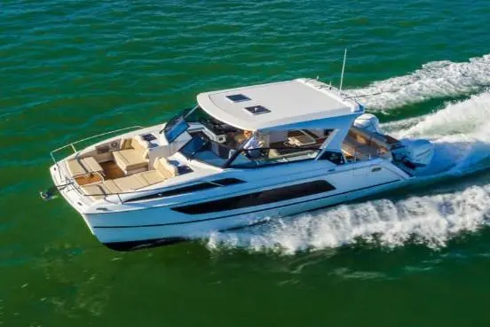 A luxury motorboat gliding over turquoise waters, leaving a wake, showcasing outdoor seating and a spacious deck.